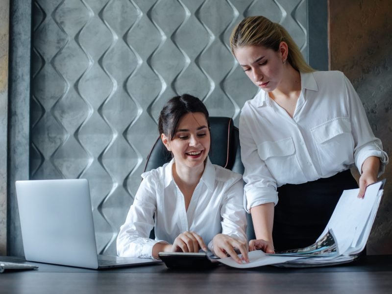 young business lady female director sitting at office desk working process business meeting working with colleague solving business tasks office collective concept